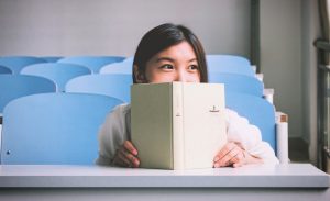 a nervous introvert hide behinds a book during class participation