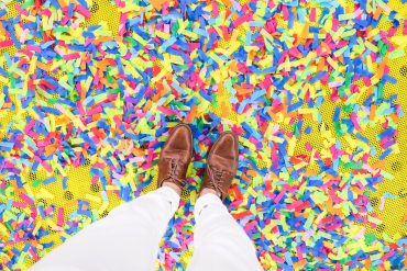 An introvert stands on confetti from a party.