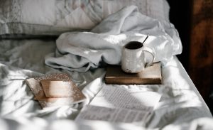 coffee, a book, and a notebook on a bed, representing how introverts can slow down and enjoy life more