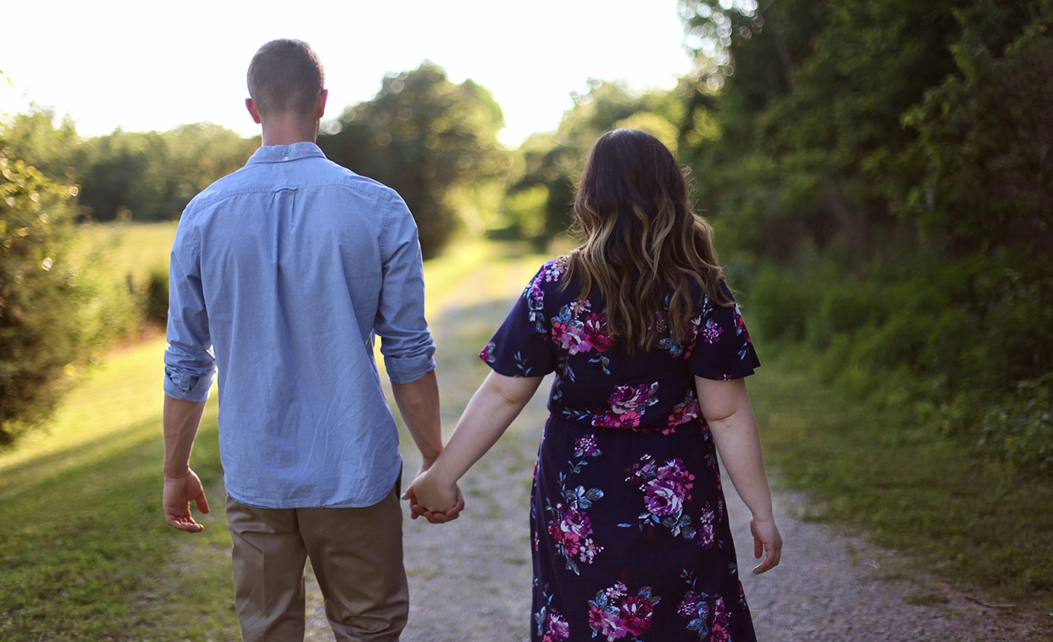A couple holding hands and walking down a path