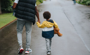 A father holds his shy, introverted child’s hand while walking down the street