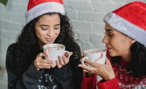 Two introverts in Santa hats drink hot chocolate