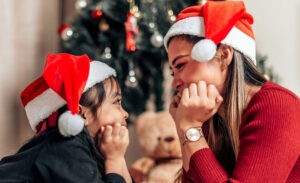 An introverted parent smiles at her daughter in front of the Christmas tree